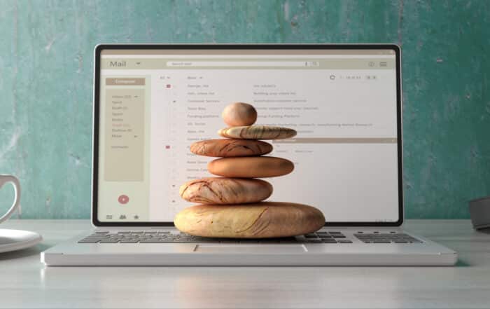 Zen stones stack on a computer laptop office desk background.